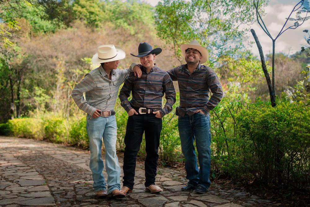 A small group of friends in cowboy hats laughing together on a country path