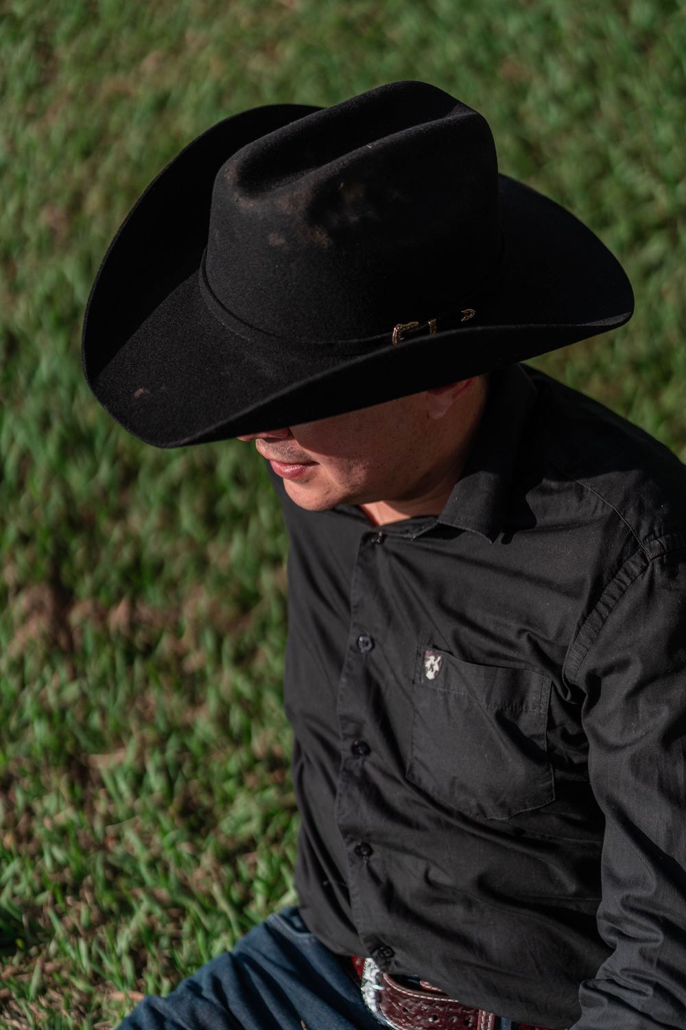 Close-up portrait of a man in a black felt cowboy hat and black shirt outdoors